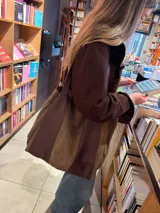 Bolso tipo shopper de gran tamaño, confeccionado en una combinación de cuero y gamuza en tonos marrones. Presenta un diseño bicolor con paneles verticales, doble asa de hombro y bolsillo interior.