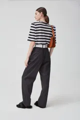 Pantalón negro de gabardina liviana de algodón, tiro alto con pinzas delanteras, bolsillos americanos y cierre metálico.