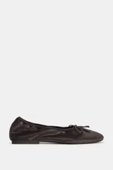 Zapato tipo bailarina de efecto terciopelo en color marrón oscuro, con detalle de lazo en la parte delantera y punta redonda.