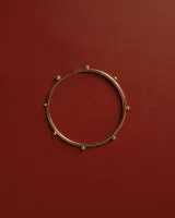 Brazalete tipo esclava dorado con detalles de pequeñas esferas distribuidas a lo largo de la pieza.
