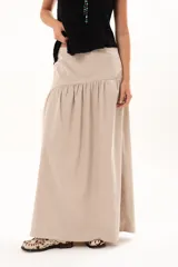 Pollera larga de corte evasé en color arena, con detalle de costura horizontal y frunces en la parte inferior que le otorgan volumen y movimiento.