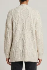 Saco abierto de punto con diseño de trenzas, color beige, con bolsillos frontales y detalle de lentejuelas integradas en el tejido.