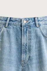 Jeans baggy fit de corte holgado en denim de algodón celeste, con tiro medio, cinco bolsillos, roturas en las rodillas y cierre frontal con cremallera y botón.