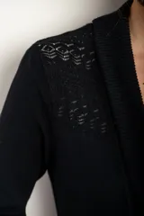 Cárdigan de punto negro con solapa ancha y mangas largas, de calce ajustado al cuerpo.