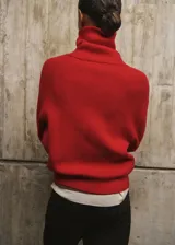 Jersey de punto grueso color rojo, de corte recto, con cuello polo amplio y cierre frontal de cremallera. Cuenta con mangas largas.