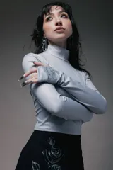 Minivestido negro con cuello alto y mangas largas. Presenta un drapeado lateral con lazos ajustables y un estampado de rosa en el frente.