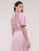 Vestido maxi de satén color rosado, con escote en V cruzado, mangas cortas amplias, cintura elastizada con lazo de ajuste y falda plisada con forro interno.