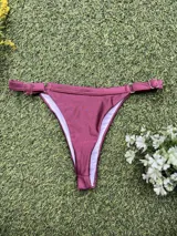 Conjunto de bikini color uva metalizado, compuesto por un corpiño triangular fijo con abertura para tazas soft y una bombacha colaless regulable.
