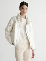 Campera puffer color blanco nacarado, con cuello alto y cierre frontal con botones a presión.