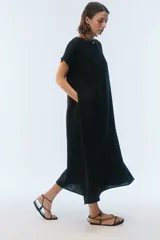 Vestido midi evasé color azul, confeccionado en lino, con escote redondo, mangas cortas con dobladillo vuelto y bolsillos laterales. Presenta un ruedo asimétrico, más largo en los laterales.