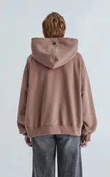 Hoodie oversize de corte crop en color marrón, confeccionado en frisa gamuzada de algodón. Presenta capucha forrada, bolsillo tipo canguro frontal y puños y ruedo acanalados.
