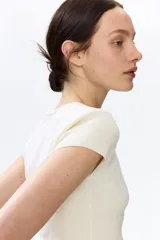 Remera corta color blanco off-white, de punto fino y suave, con diseño entallado, cuello redondo y mangas cortas.