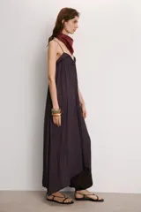 Vestido midi color morado oscuro, confeccionado en tejido satinado con efecto plisado o arrugado. Presenta escote en pico y tirantes finos ajustables. El calce es fluido y holgado.