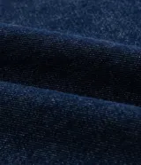 Bermuda tipo jorts de corte amplio y tiro medio, confeccionada en denim de algodón azul oscuro. Presenta diseño de cinco bolsillos, cierre frontal con botón y costuras en tono contrastante.