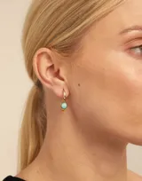 Dije de piercing dorado con forma circular y cristal celeste.