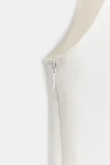 Vestido midi blanco sin mangas, con escote en V y costuras con ribetes negros a contraste. Cuenta con falsos botones decorativos en la parte delantera y una abertura central en el bajo.