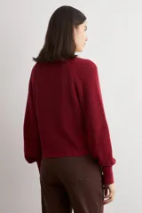Cardigan de punto acanalado color bordó, con escote en V, cierre frontal de botones y mangas largas abullonadas con puños ajustados.