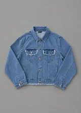 Chaqueta de denim azul con corte boxy, bolsillos frontales con solapa y detalles desflecados en los bordes y bolsillos.