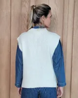 Chaleco de punto gris oscuro con diseño de trenzas y rombos en relieve, cuello redondo y terminaciones acanaladas.