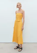 Top bandeau amarillo con diseño fruncido en el cuerpo, sin mangas y cierre de cremallera en la espalda.