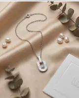 Collar de plata con cadena fina y dije rectangular con incrustación de nácar y una circonia central.