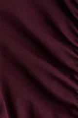 Top ajustado de algodón color bordó, con manga corta japonesa y escote en V tanto en el frente como en la espalda. Presenta costuras fruncidas que generan un efecto drapeado al centro y terminaciones con ribetes sobrehilados.