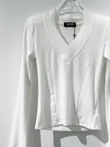 Remera de manga larga color negro, con escote en V y mangas acampanadas tipo Oxford. Confeccionada en tejido de algodón elastizado, con un diseño entallado al cuerpo.
