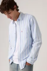 Camisa de manga larga Levi's con diseño de rayas verticales en tonos celeste y blanco. Cuenta con cuello camisero, cierre frontal de botones, un bolsillo aplicado en el pecho con etiqueta roja distintiva de la marca y dobladillo redondeado.