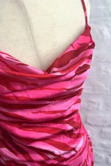 Vestido corto ajustado color rosa con estampado animal print en tonos fucsia y rosa más claro. Presenta escote drapeado tipo cowl neck y tirantes finos ajustables.