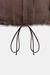 Chaqueta de cuello solapa y manga larga, confeccionada en tejido jacquard con diseño de rayas verticales. Presenta cierre frontal con botones y bajo ajustable mediante cordones.