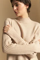 Polera de cuello alto confeccionada en tejido de punto negro, con diseño de textura acanalada en cuello, puños y ruedo, y trama vertical en mangas y espalda.