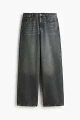 Jean de corte baggy, estilo holgado con piernas rectas, confeccionado en denim de algodón color gris oscuro con efecto lavado. Cuenta con tiro estándar, trabillas para cinto, cierre frontal con botón y cinco bolsillos clásicos.