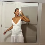Vestido blanco de breteles finos, con escote en V y falda midi con volados.