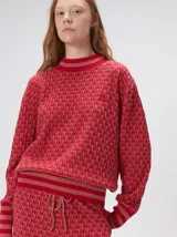 Sweater de tejido de punto jacquard con diseño geométrico, cuello redondo y puños acanalados en contraste de color verde y beige.