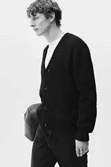 Cárdigan negro de punto peludo suave, con cuello en V pronunciado y cierre frontal de botones. Presenta remates acanalados en puños y bajo.