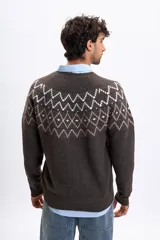 Buzo de tejido de punto en color marrón con diseño jacquard geométrico en la parte superior del pecho y hombros. Presenta cuello redondo, mangas largas y puños acanalados.