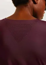 Camiseta deportiva de manga corta en color negro, confeccionada en tejido técnico transpirable con detalles de perforaciones laterales para mayor ventilación. Presenta un corte ajustado y logo reflectante en el ruedo.