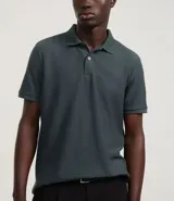 Camisa polo de corte regular, color verde oscuro, confeccionada en tejido texturizado. Presenta cuello clásico con botones frontales y mangas cortas.