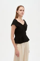 Blusa de lino color blanco, con cuello en V, pinzas de entalle y diseño al cuerpo con faldón acampanado.