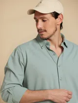Camisa de manga larga color verde claro, con cuello clásico y cierre frontal con botones.