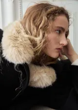 Chaqueta negra de corte corto y holgado, confeccionada con mezcla de lana. Cuenta con cuello ancho y solapa de piel sintética en tono beige claro, cierre frontal con botones oscuros y mangas largas amplias.