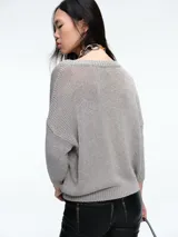 Sweater de punto con brillo, de corte relajado y escote en V. Presenta hombros caídos y mangas largas con puños acanalados.