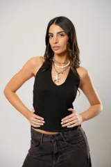 Top negro con escote halter y espalda semi descubierta, confeccionado en tejido con textura sutil. Presenta un diseño ajustado al cuerpo y logo bordado en la parte inferior de la espalda.