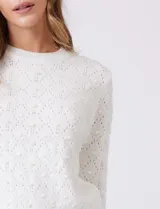 Buzo blanco de tejido calado con perlas bordadas, cuello a la base y manga larga, de la marca Nanette.