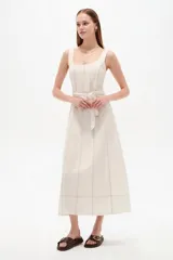 Vestido midi de lino color blanco con cuello cuadrado, sin mangas, detalle de pespuntes a contratono y cinturón con hebilla integrada en la cintura.