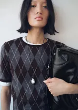 Collar largo con cordón negro ajustable y dije metálico de diseño orgánico y minimalista.