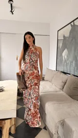 Vestido largo tipo globo con cuello halter y espalda descubierta, confeccionado en tela fluida con estampado botánico y geométrico en tonos tierra.