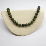 Collar de cuentas esféricas de jade verde, con separadores de hilo lila y cierre de mosquetón dorado.