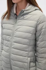 Campera acolchada tipo puffer, color beige claro, con capucha y cierre frontal. Presenta costuras horizontales y un calce entallado.