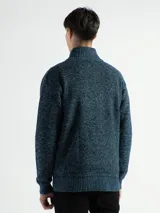 Campera de punto con cierre frontal, cuello alto y forro interno. Presenta un diseño de tejido jaspeado con puños y ruedo acanalados, e incluye un pequeño aplique de marca en la parte inferior.